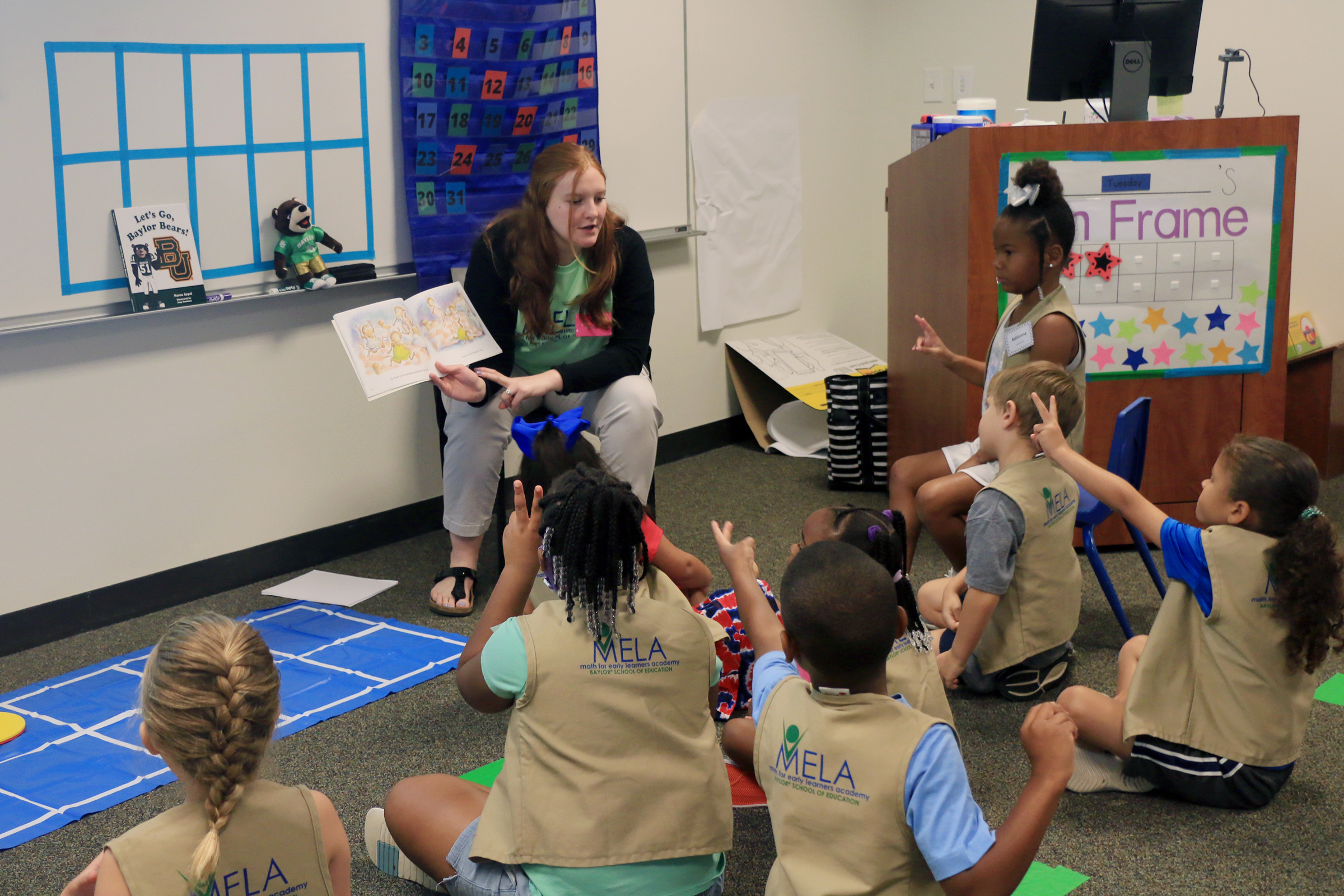 Students learning math from teacher reading a book at Baylor Math for Early Learners Academy