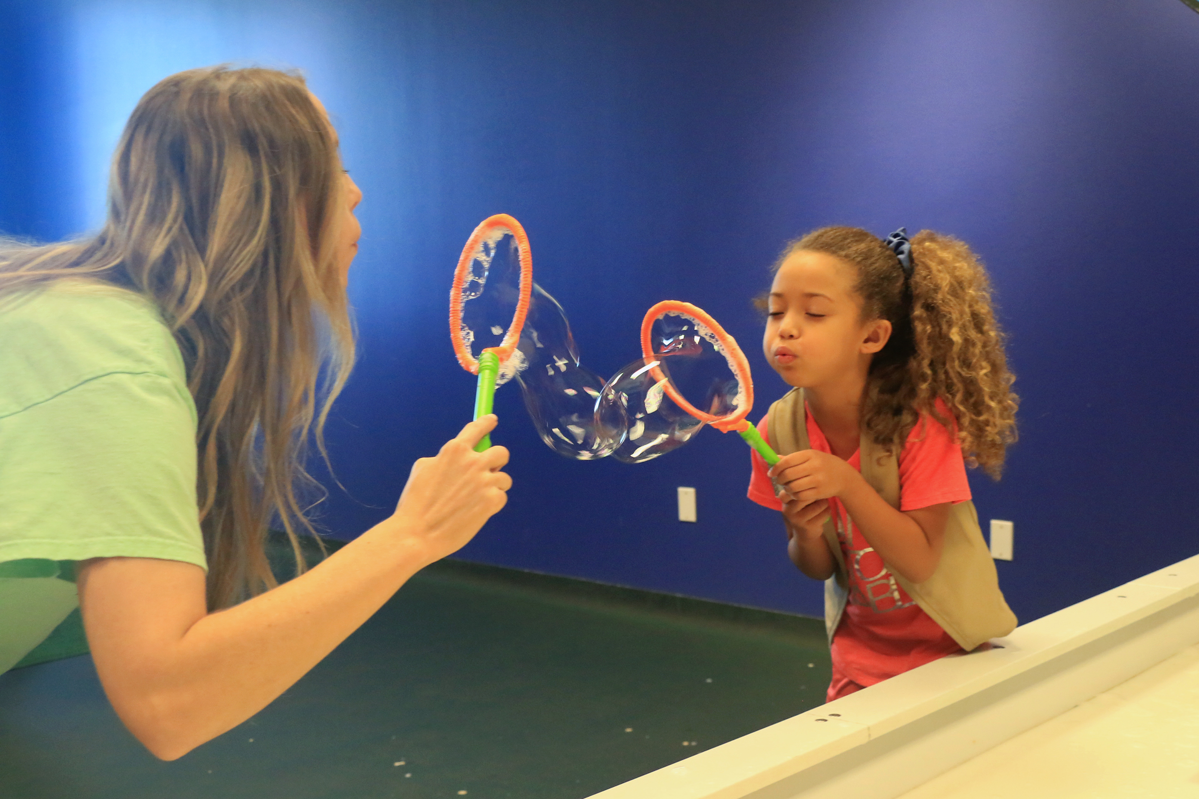 Student lblowing bubbles in Mayborn bubble room at Baylor Math for Early Learners Academy